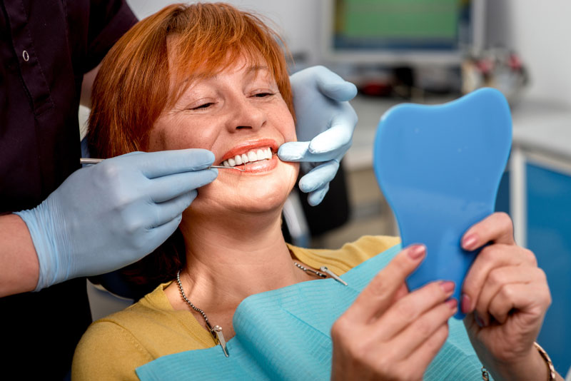 Patient smiling in front of the mirror after their dental procedure